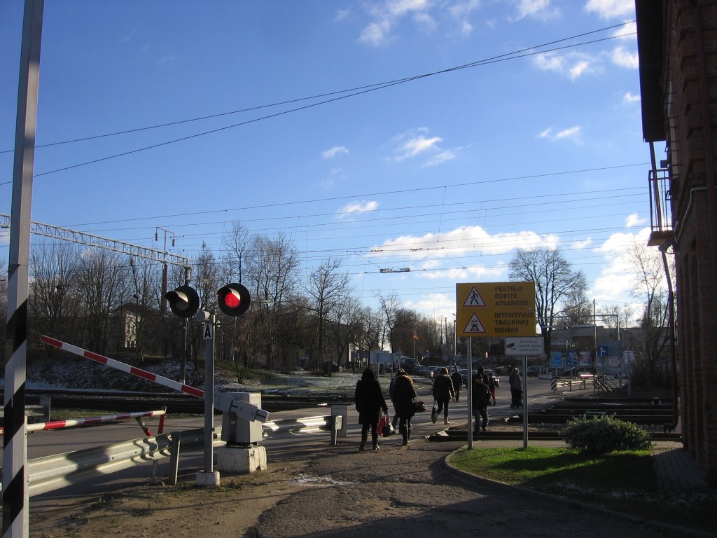 Per Lentvario geležinkelio perėją  skuba pėstieji, nepaisydami atvažiuojančio traukinio